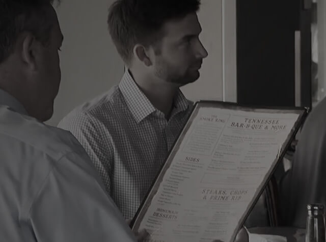 Black and white closeup of a dinner reading a menu